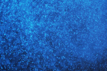 Abstract festive background with selective focus. Bright blue particles on dark background. Splashes, space, energy flow