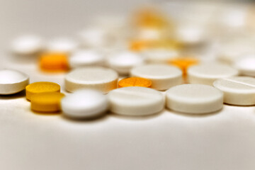 A sprinkle of yellow and white tablets, close-up front view. Blurred background. Medicines are out of focus. Medical background. Antibiotics