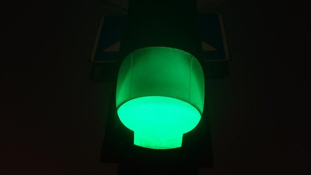 Close up view of green color on the traffic light. Green illuminated street light at night with black background