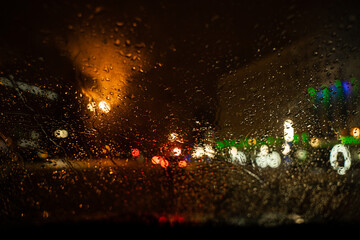 View of the night city through the wet car window with drops