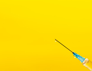 disposable syringe in hand on yellow background
