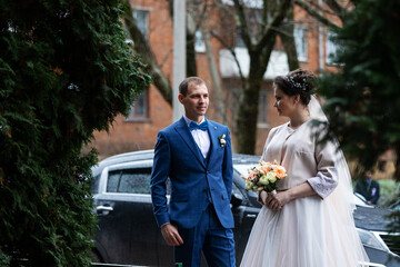 the bride and groom near the car, hug and kiss their loved one at the wedding, the family at the winter photo shoot with the wedding cortege
