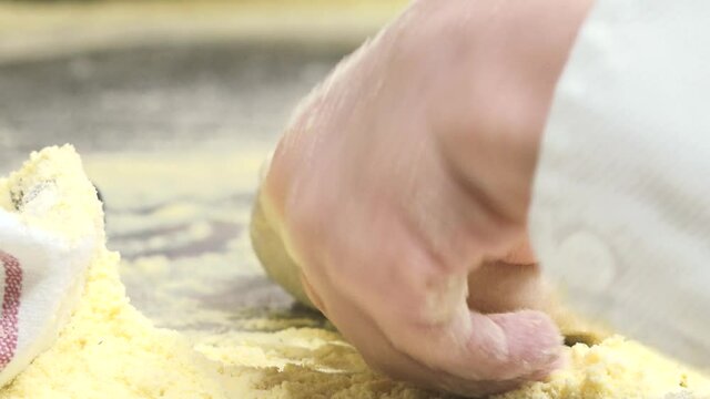 A child kneads a pizza dough with small hands
