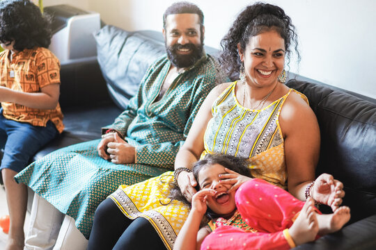 Happy indian family having fun at home sitting on sofa - Focus on mother