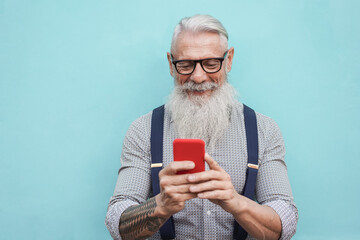 Happy senior hipster man using mobile phone outdoors in the city - Focus on face