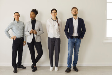 Full length group of young diverse office workers or job candidates. Full body team of different multiracial business people in formal and smart casual wear waiting near wall looking away or at camera - Powered by Adobe