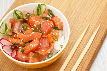 Hawaiian poke with salmon, sesame seeds and boiled rice on wooden board.