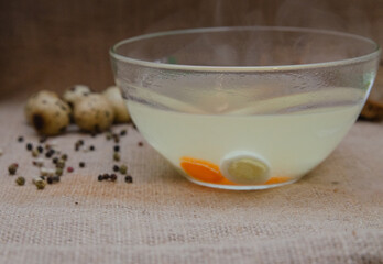 Chicken broth with quail eggs and herbs on burlap. Diet food.