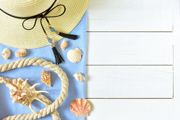 Sea collage with seashells, straw hat with a ribbon and sea rope on the blue and white wooden background, top view.
