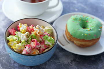  popcorn in a bowl and donuts on plate on black background 