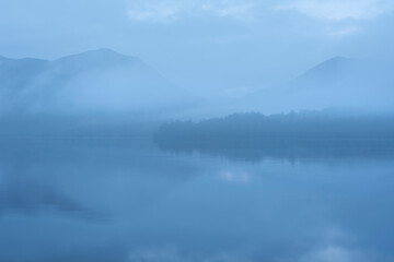 Fototapeta na wymiar Beautiful landscape image of misty Derwentwater in Lake District on cold Winter morning