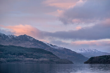 Majestic landscape image across Loch Lomond looking towards snow capped Ben Lui mountain peak in Scottish Highlands