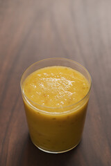 Mango lulo smoothie on walnut wood table with copy space
