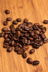 Brown roasted coffee beans small pile on a wooden board macro shot