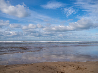 Beautiful empty beach with tide coming in, blue sky in winter, UK.
