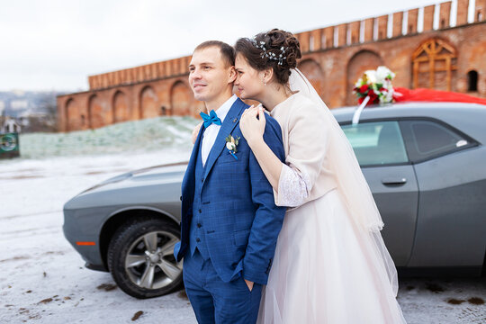 the bride and groom near the car, hug and kiss their loved one at the wedding, the family at the winter photo shoot with the wedding cortege