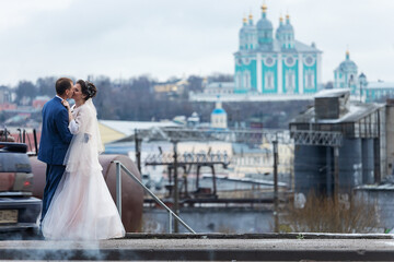 the bride and groom on the background of a church, religious lovers, a wedding walk in winter, a man and a woman gently kiss and smile hugs