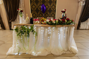 decorations with flowers at the wedding, the interior of the restaurant is prepared by the decorator for the holiday, beautiful fresh flowers in vases on the table, a bouquet as a gift from the guests