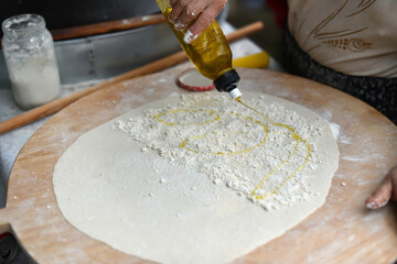 Turkish Food. Gozleme (Turkish stuffed flatbread) cooking process in traditional style. Adding olive oil inside  