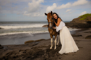 Beautiful smiling woman leading horse by its reins. Cuddling horse. Love to animals. Asian woman...