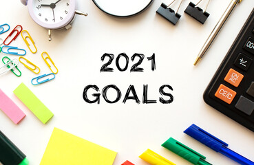 Office desk table with calculator, pens and other stationery. Text on the 2021 GOALS.