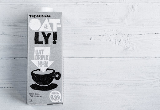 Oatly milk carton on a wooden table. Oatly is a dairy free vegan milk alternative. London / UK - September 2nd 2019
