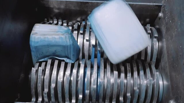 The plastic shredder recycles plastic cans. Close-up of cutters