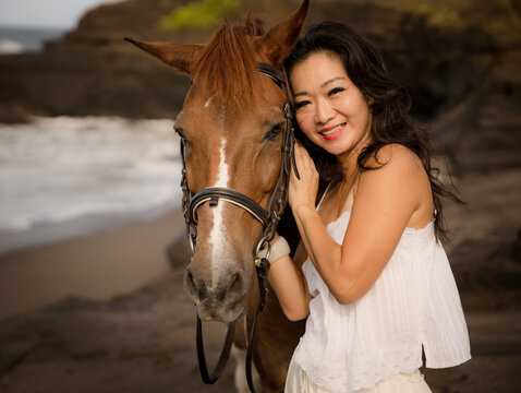 Portrait of smiling woman and brown horse. Asian woman hugging horse. Romantic concept. Love to animals. Nature concept. Bali - Powered by Adobe
