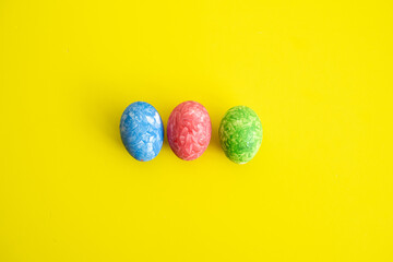 Three easter colored eggs on yellow background. Easter is  main event for believers, timed coincide...