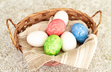 Many different colors eggs in basket with beautiful towel for easter on the beige background. Easter is the main event for believers, timed coincide with resurrection of Jesus Christ. Close-up