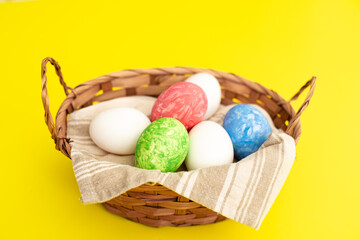 Many different colors eggs in basket with beautiful towel for easter on the yellow background....