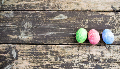 Three easter colors eggs are arranged on wooden background. Easter is  main event for believers,...