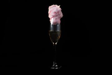 Glass of champagne with cotton candy on black background.