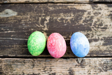 Three easter colored eggs on wood background. Easter is  main event for believers, timed coincide with resurrection of Jesus Christ.  Close-up