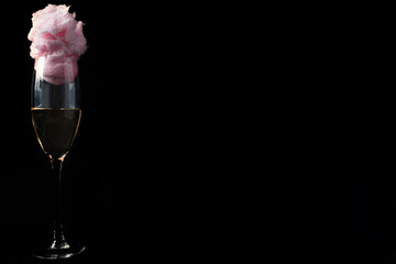 Glass of champagne with cotton candy on black background.