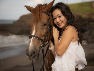 Fototapeta premium Portrait of Asian woman and brown horse. Woman hugging horse. Romantic concept. Human and animals relationship. Nature concept. Bali