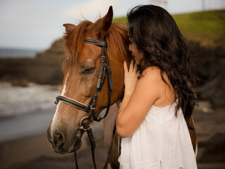 Obraz premium Portrait of Asian woman and brown horse. Woman hugging and kissing horse. Romantic concept. Human and animals relationship. Nature concept. Bali
