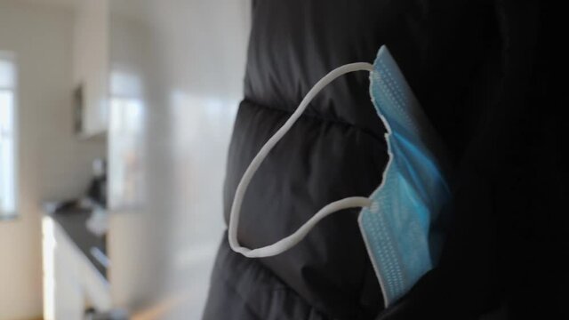 Close up view of covid mouthguard sticking out from a pocket on a black down jacket 
