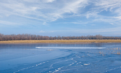 melting spring lake under a blue cloudy sky