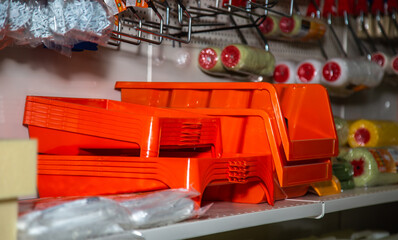 In a hardware store, on a shelf, there is a tray for a roller and paint and equipment for painting...