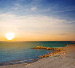 Obraz premium sea bay with stony coastline at the sunset
