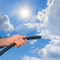 closeup people hand holding a watering hose on the sunny sky background
