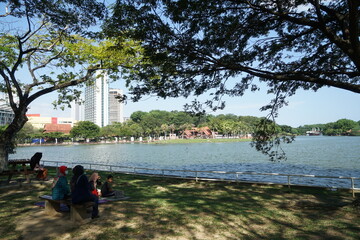Recreational park lake view with people resting on a bench, selective focus.