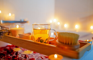Herbal mint tea on bathtub tray with candles, lavender and salt during spiritual aura cleansing...