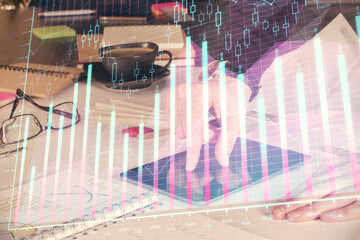 Double exposure of man's hands holding and using a digital device and forex graph drawing. Financial market concept.