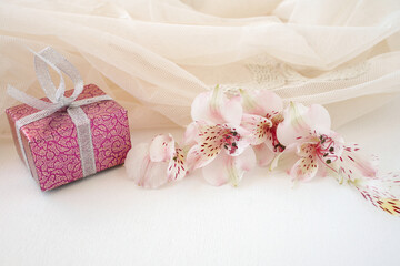 pink flowers of astroemeria and gift box on delicate background. postcard for Valentine's Day
