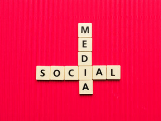 MEDIA SOCIAL crossword made from square letter tiles on red background.