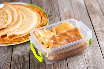 Frozen pancakes in container on a wooden background. Semi-finished pancakes