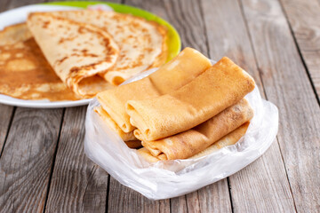 Frozen pancakes in a plastic bag on a wooden background. Semi-finished pancakes