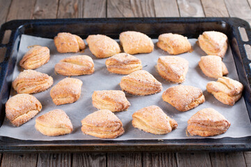 Curd sugar cookies crow's feet on a baking sheet on a wooden table. Cottage cheese cookies